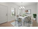 Bright dining room with modern chandelier, sleek white table, and stylish gray chairs at 11415 Fort Lauderdale Pl, Venice, FL 34293