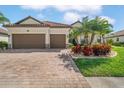 Charming single-Gathering home with a brick paver driveway, two-car garage, and well manicured tropical landscape at 13325 Caravaggio Ct, Venice, FL 34293