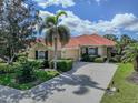 Lovely one-story home with a terracotta roof, lush landscaping, and a paved driveway leading to the garage at 174 Treviso Ct, North Venice, FL 34275