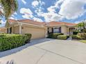 Beautiful single-story home with a terracotta tile roof, mature landscaping, and an attached two-car garage at 174 Treviso Ct, North Venice, FL 34275