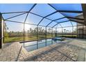 Screened-in pool and spa with brick pavers, overlooking a green expanse at 17449 Luminous Ave, Venice, FL 34293