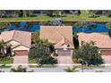 Aerial view of home showcasing its tile roof, paver driveway, and beautiful waterfront location on a serene pond at 19651 Quisto St, Venice, FL 34293