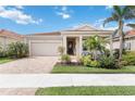 Inviting single-story home with a well-manicured lawn, brick driveway, and covered front entrance at 20389 Minuet Pl, Venice, FL 34293