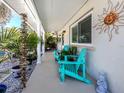 Inviting covered front porch with bright blue Adirondack chairs and decorative sun art at 229 San Marco Dr, Venice, FL 34285