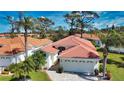 A peaceful home showcasing a well-maintained red tile roof, a two-car garage, and landscaping with mature palm trees at 4398 Summertree Rd, Venice, FL 34293