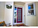 Inviting entryway with a decorative wreath, red front door, a cute rug, and a window with white trim at 4398 Summertree Rd, Venice, FL 34293