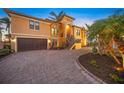 Elegant two-story home boasts a brick driveway, two-car garage, and tropical landscaping at 471 Bayshore Rd, Nokomis, FL 34275