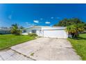 A well-maintained white single-story home features a two-car garage, driveway, and a green lawn with palm trees at 501 Dona Dr, Nokomis, FL 34275