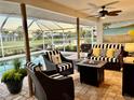 The screened-in lanai offers comfortable seating and views of the pool and the backyard pond at 557 Warwick Ct, Venice, FL 34293