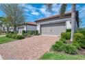 Exterior elevation with a brick driveway and tile roof, showcasing the home's curb appeal at 11810 Tapestry Ln, Venice, FL 34293