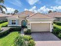 Charming home featuring a clay tile roof, a brick paver driveway, and a quaint blue front door at 129 Cipriani Way, North Venice, FL 34275