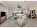 Bright living room featuring neutral tile flooring, a ceiling fan, and sliding doors leading to the pool area at 129 Cipriani Way, North Venice, FL 34275