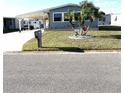 Quaint gray home with a mailbox, complemented by vibrant green lawn and palm trees at 199 Palm Harbor Dr, North Port, FL 34287