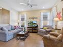 Comfortable living room featuring tile floors, a ceiling fan, and plenty of natural light from the large windows at 20390 Cavallo Ct, Venice, FL 34292