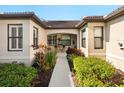 Inviting entryway with decorative plants, windows with white shutters, and an arched covered porch at 2059 Batello Dr, Venice, FL 34292