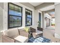 Cozy covered porch with seating and a blue rug, featuring a view of the home's entrance and garage at 228 Caserta Ct, North Venice, FL 34275