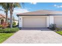 Exterior garage with a brick driveway, well maintained landscaping and a large beige garage door at 24044 Canterwood Way, Venice, FL 34293