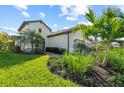 Exterior view of a charming home with manicured lawn and decorative palm trees at 27440 Janzen Ct, Englewood, FL 34223