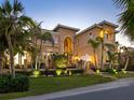 Elegant two-story home with lush landscaping, manicured lawn, and exterior lighting enhancing its curb appeal at 2821 Casey Key Rd, Nokomis, FL 34275