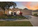 Charming single-story home with manicured lawn, mature landscaping and a two car garage at sunset at 312 Londonderry Dr, Sarasota, FL 34240
