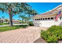 Brick driveway leads to the attached garage with a meticulously maintained lawn and manicured shrubbery at 4301 Nizza Ct, Venice, FL 34293