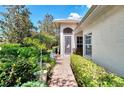 Inviting front entrance with decorative door, lush landscaping, and a brick pathway leading to the door at 4301 Nizza Ct, Venice, FL 34293
