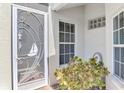 Close-up of the front door with decorative security screen, sidelight window and lush green landscaping at 4301 Nizza Ct, Venice, FL 34293