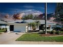 Charming single-story home with a well-manicured lawn, mature trees, and a two-car garage at 562 Silk Oak Dr, Venice, FL 34293