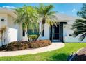 Inviting front entrance features lush landscaping and a charming walkway to the screened porch at 562 Silk Oak Dr, Venice, FL 34293