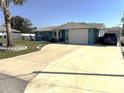 Well-maintained blue home featuring a spacious driveway, garage, and covered carport at 599 Carmel Rd, Venice, FL 34293