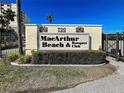 MacArthur Beach & Racquet Club community sign with palm trees and manicured landscaping at 700 Golden Beach Blvd # 224, Venice, FL 34285