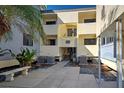 Exterior condo building with light yellow siding, balconies, and lush landscaping at 700 Golden Beach Blvd # 224, Venice, FL 34285