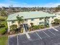 Yellow two-story condo building with a green roof, lush landscaping, and on-site parking at 944 Capri Isles Blvd # 103, Venice, FL 34292