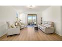 Bright living room with hardwood floors, neutral paint, and sliding doors to a screened lanai at 9900 Haze Dr, Venice, FL 34292
