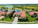 Beautiful aerial view of home with tile roof, complemented by lush landscaping and serene lake backdrop at 10742 Ironbridge Dr, Venice, FL 34293