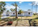 Inviting home exterior with a covered carport, complemented by a palm tree and vibrant landscaping at 1075 Falcon Rd, Venice, FL 34293