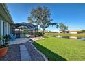 Expansive backyard with a screened-in lanai, lush green lawn, and peaceful waterfront view at 1125 Deardon Dr, Venice, FL 34292