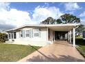 Single-story home featuring carport and sidewalk leading to a cozy screened-in patio at 16 Nautical Dr, North Port, FL 34287