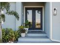 Elegant front entry with double glass doors framed by potted plants and modern lighting at 177 Ingram Blvd, Rotonda West, FL 33947
