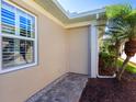 Neutral home exterior featuring a security shutter, decorative window, and lush, tropical landscaping at 1833 Lancashire Dr, Venice, FL 34293