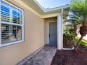 Neutral home exterior with decorative window and front door entry with stone pathway and mature landscaping at 1833 Lancashire Dr, Venice, FL 34293