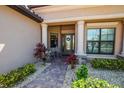 Elegant front entrance with decorative columns, stone accents, and beautiful landscaping at 20806 Valprato Ct, Venice, FL 34293