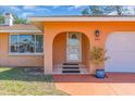 Close up on a front door featuring an arched entry, decorative glass, and a welcoming porch with potted plants at 491 Conrad Rd, Venice, FL 34293