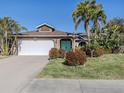 Inviting home showcasing a well-maintained front yard, a two-car garage, and a welcoming entrance with vibrant tropical plants at 613 Sugarwood Dr, Venice, FL 34292