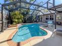Serene screened-in pool area featuring a waterfall, lush landscaping, and comfortable lounge seating for ultimate relaxation at 613 Sugarwood Dr, Venice, FL 34292
