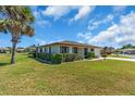 A low-angle view of a single-story home with a well-kept lawn, mature tree, and manicured hedges at 761 Vivienda South Ct # 14, Venice, FL 34293