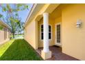 Charming front entrance features a classic column, decorative lighting, and a view of the well-maintained lawn and serene lake at 9019 Eagle Bay Ct, North Port, FL 34287