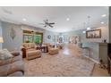 Open concept living room with a large patterned rug, ceiling fan, and an adjoining dining area at 9839 Nostalgia Pl, Englewood, FL 34223