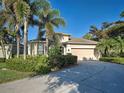 Charming single-story home featuring a manicured lawn, tropical trees, and a two-car garage at 117 Altesino Ct, Venice, FL 34292