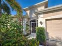 Home's attractive front entry featuring a screened door, tidy landscaping, and an attached two-car garage at 117 Altesino Ct, Venice, FL 34292